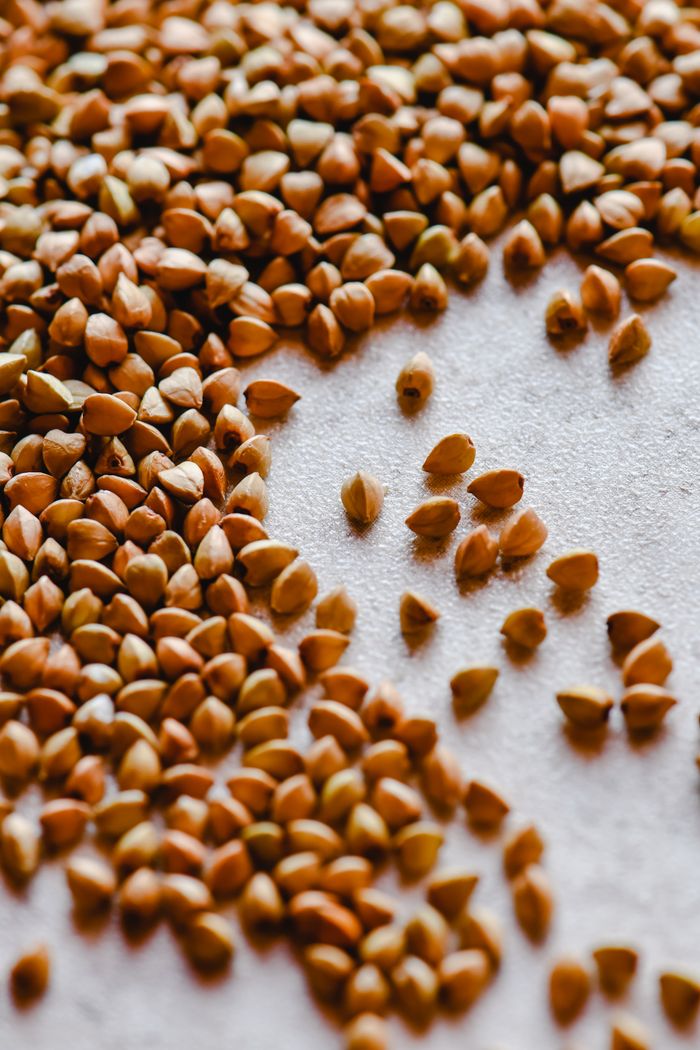 Detailed view of scattered buckwheat seeds on a textured surface, emphasizing their organic texture.